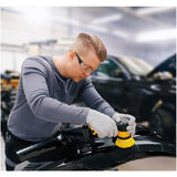 Person working on a car with a polishing machine in a garage setting