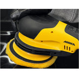 Yellow and black Mirka polisher being used on a car surface.