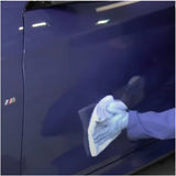 Person waxing a blue car with a white cloth